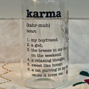 May include: A clear glass can with a black and white design that says "karma" and defines it as "my boyfriend, a god, the breeze in my hair on the weekend, a relaxing thought, sweet like honey, a cat purring in my lap cause it loves me".
