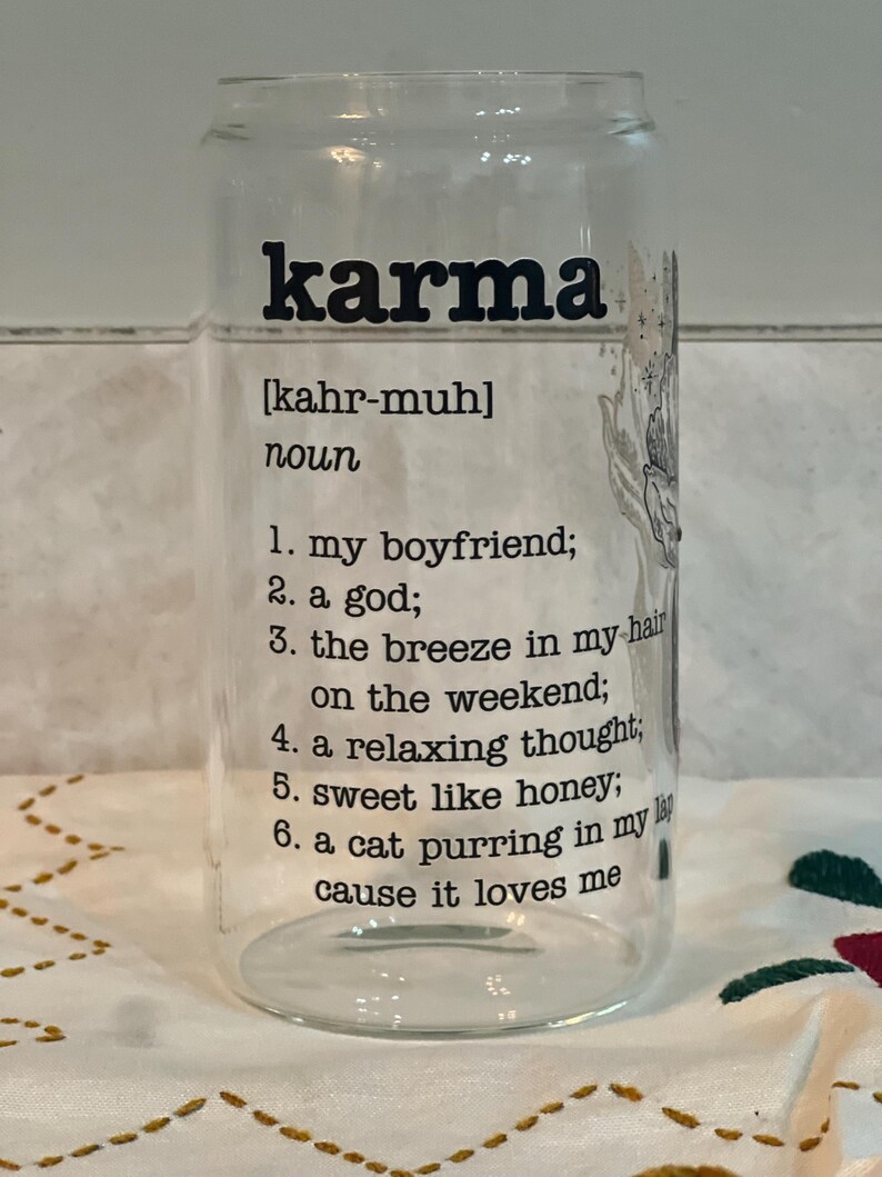 May include: A clear glass can with a black and white design that says "karma" and defines it as "my boyfriend, a god, the breeze in my hair on the weekend, a relaxing thought, sweet like honey, a cat purring in my lap cause it loves me".