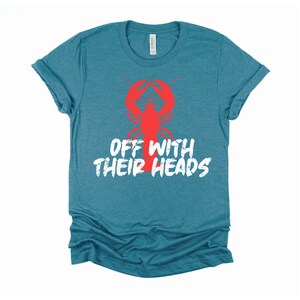 K&ouml;nnte beinhalten: Tealblaues T-Shirt mit einem roten Hummer-Motiv und dem Text "Off with their heads" in Wei&szlig;.