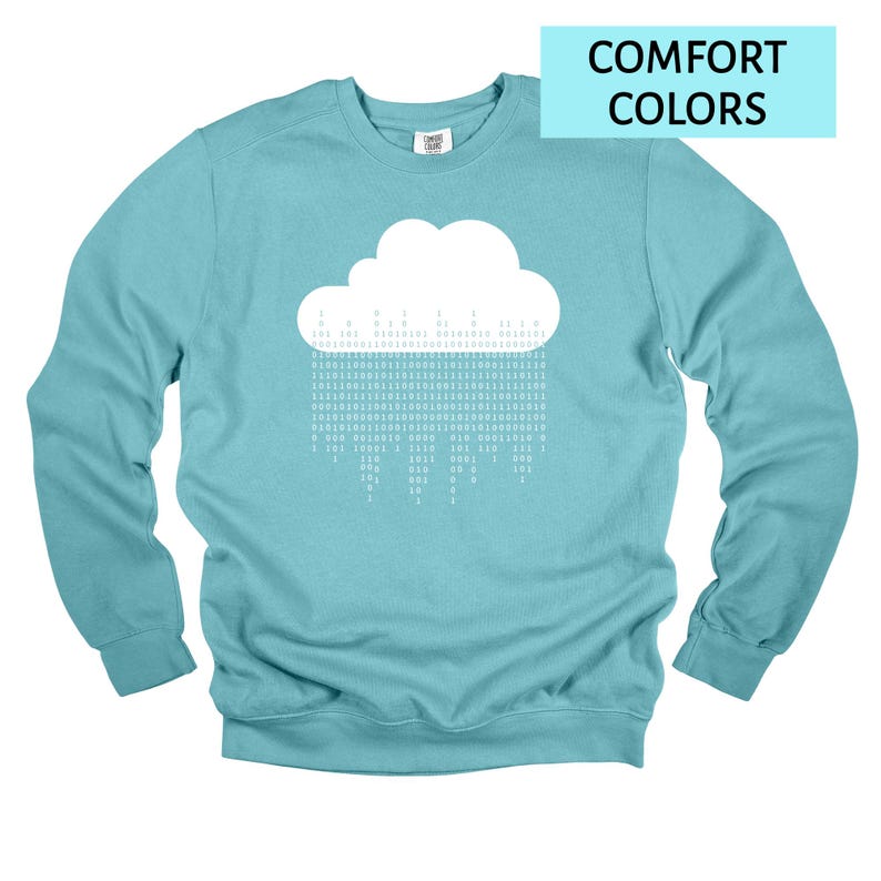 Op de afbeelding: Een lichtblauw sweatshirt met een witte wolkengrafiek en binaire code regen. De tekst "COMFORT COLORS" staat in een lichtblauwe rechthoek rechtsboven. De sweatshirt heeft lange mouwen en een ronde hals.