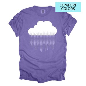 Pode incluir: Camiseta roxa com um desenho de nuvem branca e chuva de c&oacute;digo bin&aacute;rio. O texto "COMFORT COLORS" est&aacute; em um ret&acirc;ngulo azul claro. Gola redonda e mangas curtas.