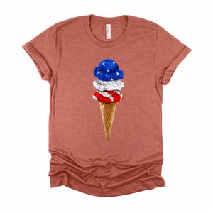 May include: A red, white, and blue ice cream cone with three scoops of ice cream. The top scoop is blue with white stars, the middle scoop is white, and the bottom scoop is red with white stripes. The cone is a waffle cone.