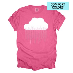 Pode incluir: Camiseta rosa com um desenho de nuvem branca e chuva de c&oacute;digo bin&aacute;rio. O texto "COMFORT COLORS" est&aacute; em um ret&acirc;ngulo azul. A camiseta &eacute; feita de um material macio e confort&aacute;vel.