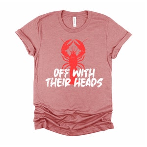K&ouml;nnte beinhalten: Ein heidefarbenes rotes T-Shirt mit einem roten Hummer-Motiv und dem Text "Off with their heads" in Wei&szlig;.