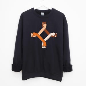 May include: A black sweatshirt with a graphic of four arms of different skin tones intertwined in a circle. The arms are stylized and have a vintage look.