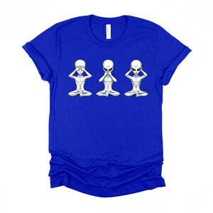 May include: A royal blue t-shirt featuring a graphic of three grey aliens in a 'see no evil, hear no evil, speak no evil' pose.