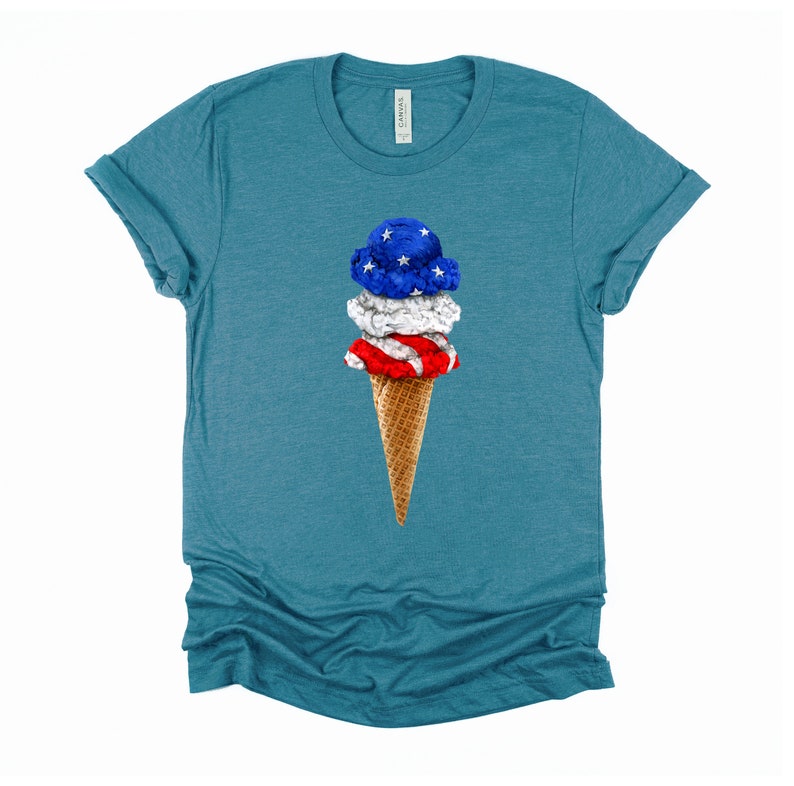 May include: A teal blue t-shirt with a graphic of a three-scoop ice cream cone. The ice cream is decorated with the colors of the American flag: red, white, and blue.