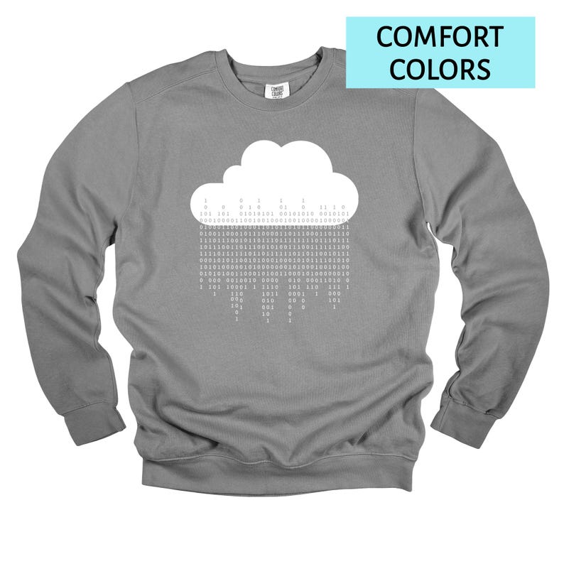 Op de afbeelding: Een grijze sweatshirt met een witte wolkengrafiek en binaire code regen. De tekst "COMFORT COLORS" staat in een lichtblauwe rechthoek. De sweatshirt heeft lange mouwen en een ronde hals.