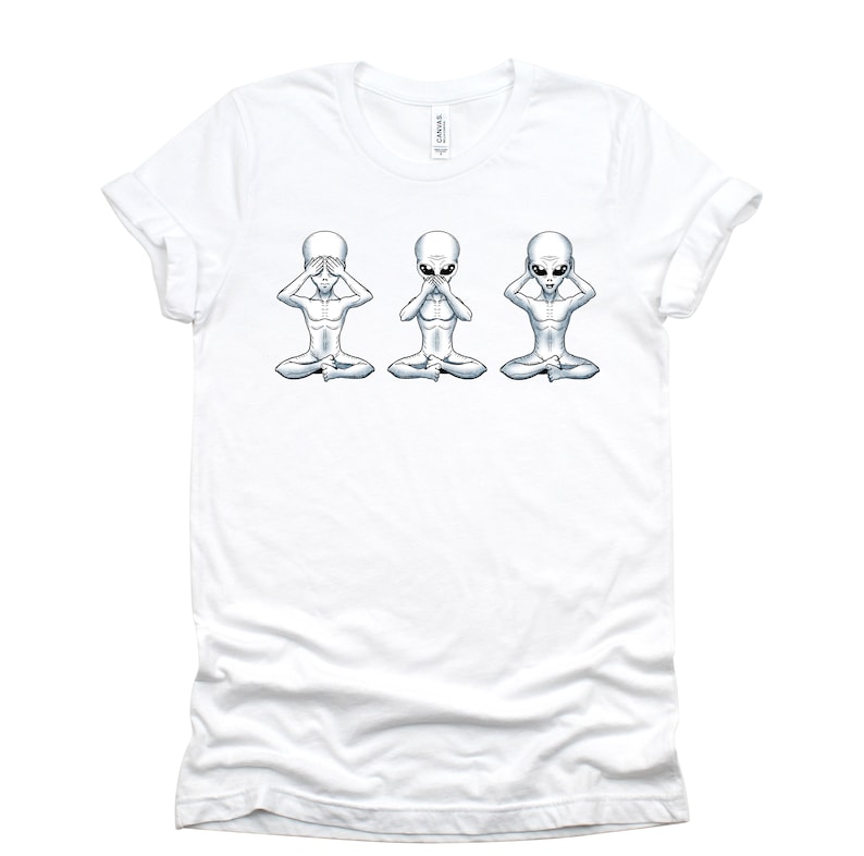 May include: White t-shirt featuring a graphic of three grey aliens in a row, each with their hands covering their eyes, mouth, and ears, respectively. The aliens are seated with their legs crossed.