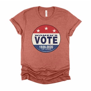May include: A red heather t-shirt with a blue and red circular graphic that says "Women's Vote 1920-2020 100 Years 19th Amendment".