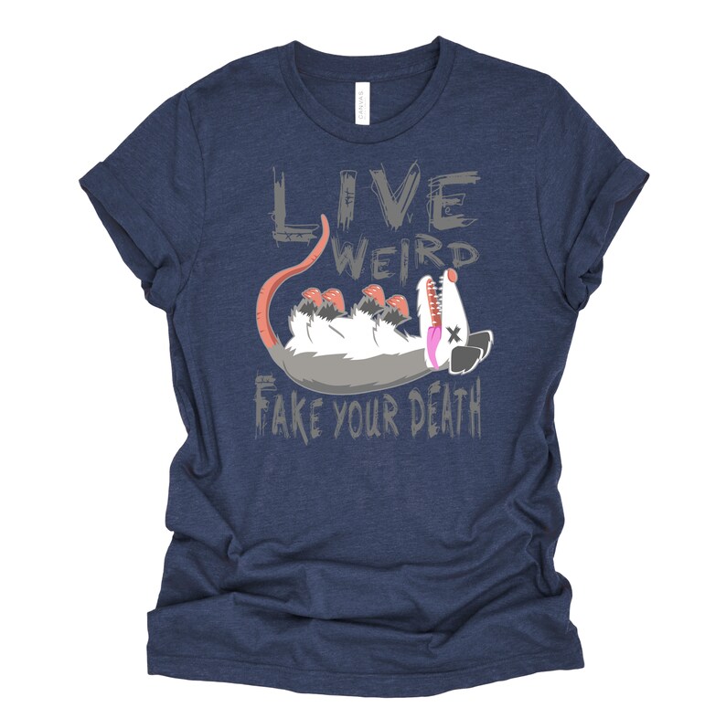 Op de afbeelding: Een marineblauw t-shirt met een grijze afbeelding van een opossum die dood speelt. De tekst "Live Weird Fake Your Death" is in grijs op het t-shirt gedrukt.