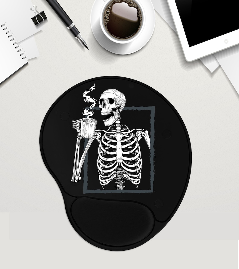 May include: Black round mouse pad featuring a white skeleton illustration holding a cup of coffee. The skeleton is framed in a grey rectangle.