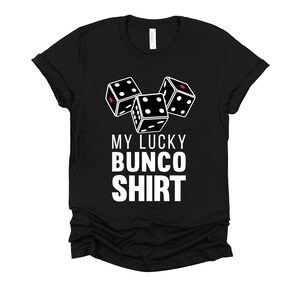 May include: Black t-shirt with white text that says "My Lucky Bunco Shirt" and a graphic of three white dice with red dots.