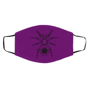 K&ouml;nnte beinhalten: Eine violette Gesichtsmaske mit einer schwarzen Illustration einer Tarantel. Die Maske hat schwarze Ohrschlaufen und besteht aus einem weichen Stoff. Das Tarantel-Design ist detailliert und mittig auf der Maske platziert.