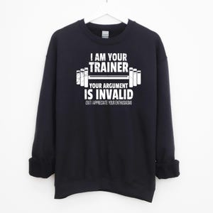 May include: Black sweatshirt with a white graphic print that says "I am your trainer, your argument is invalid (but I appreciate your enthusiasm)" with a barbell graphic.