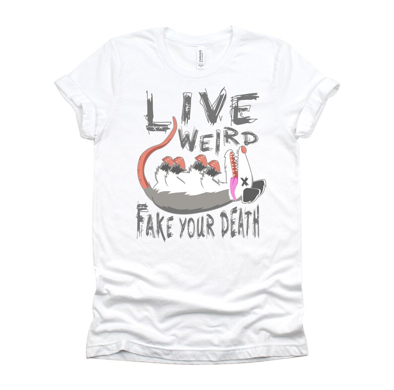 Op de afbeelding: Wit T-shirt met een grijze afbeelding van een opossum met de tekst "Live Weird Fake Your Death" erop.