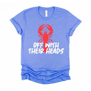 K&ouml;nnte beinhalten: Ein hellblaues T-Shirt mit einem roten Hummer-Motiv und dem Text "Off with their heads" in Wei&szlig;.
