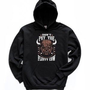 May include: Black hooded sweatshirt with a brown bison illustration and the text "Don't Pet the Fluffy Cow" in white.