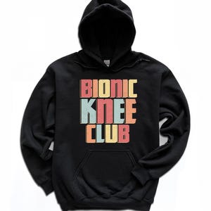 May include: Black hooded sweatshirt with the text "Bionic Knee Club" in colorful retro-style lettering.