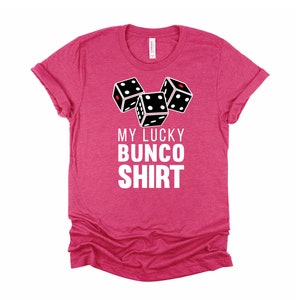 May include: Pink t-shirt with a white graphic of three dice and the text "My Lucky Bunco Shirt".