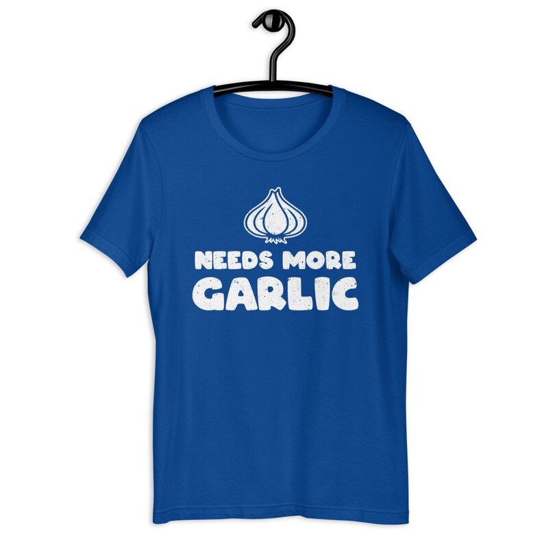 May include: A royal blue t-shirt with a white graphic of a garlic clove and the text "Needs More Garlic".
