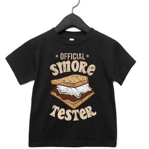 May include: Black t-shirt with a graphic of a s'more and the text "OFFICIAL SMORE TESTER" in a distressed font.