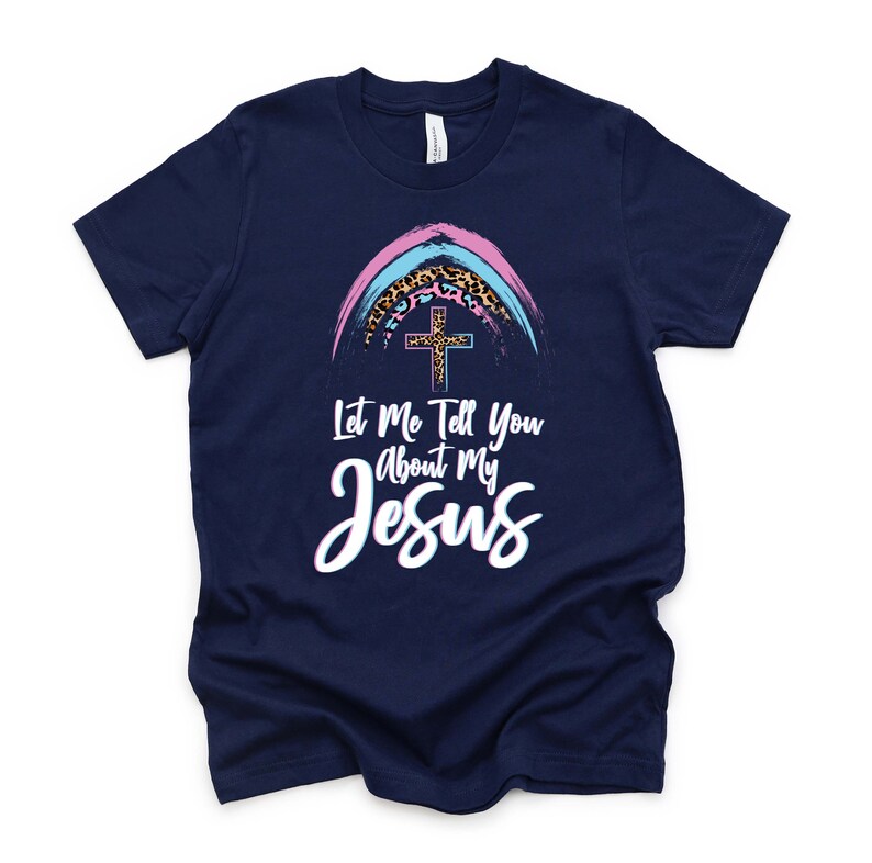 May include: A navy blue t-shirt with a rainbow and cross graphic. The text "Let Me Tell You About My Jesus" is printed on the shirt.