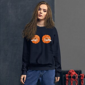 May include: A black sweatshirt with a graphic of two orange pumpkins with skeleton hands. The pumpkins are centered on the chest of the sweatshirt.