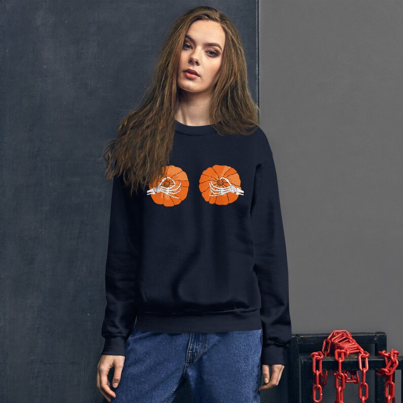 May include: A black sweatshirt with a graphic of two orange pumpkins with skeleton hands. The pumpkins are centered on the chest of the sweatshirt.