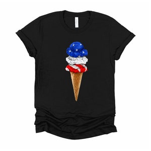 May include: A black t-shirt with a graphic of a three-scoop ice cream cone. The ice cream is red, white, and blue, resembling the American flag.