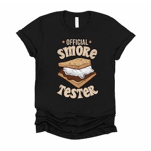 May include: Black t-shirt with a graphic of a s'more and the text "OFFICIAL s'more TESTER" in a vintage style font.