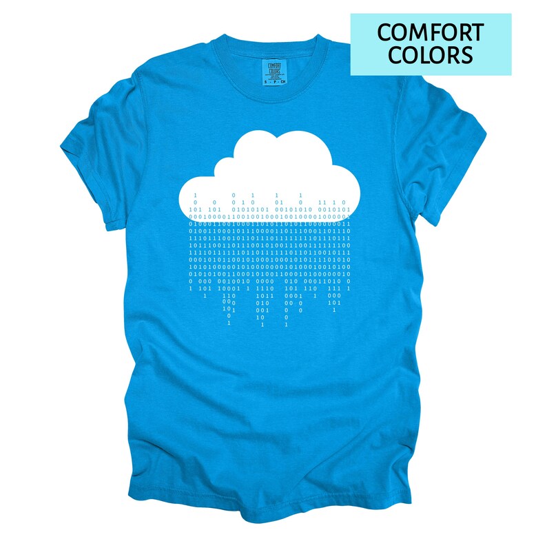 Pode incluir: Camiseta azul turquesa com um gr&aacute;fico de nuvem branca. O design da nuvem &eacute; feito de c&oacute;digo bin&aacute;rio, com as palavras "COMFORT COLORS" em um ret&acirc;ngulo azul claro no canto superior direito.
