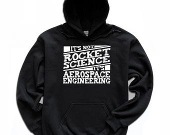 May include: Black hooded sweatshirt with a front pocket and white text that reads "IT'S NOT ROCKET SCIENCE IT'S AEROSPACE ENGINEERING". The sweatshirt has a drawstring hood and long sleeves.