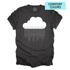 Pode incluir: Camiseta cinza escuro com um gr&aacute;fico de nuvem branca e c&oacute;digo bin&aacute;rio chovendo. O texto "COMFORT COLORS" est&aacute; em um ret&acirc;ngulo azul claro. Uma camiseta confort&aacute;vel e casual.