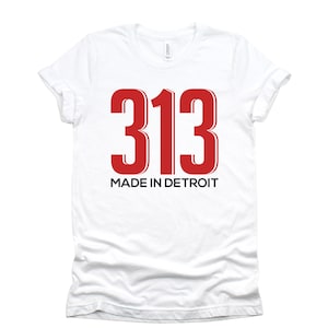 May include: White t-shirt with a red 313 graphic and the text "MADE IN DETROIT" printed on the front.