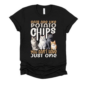 May include: Black t-shirt with a white graphic that says "Cats are like potato chips you can't have just one". The graphic also features four cats in a row.