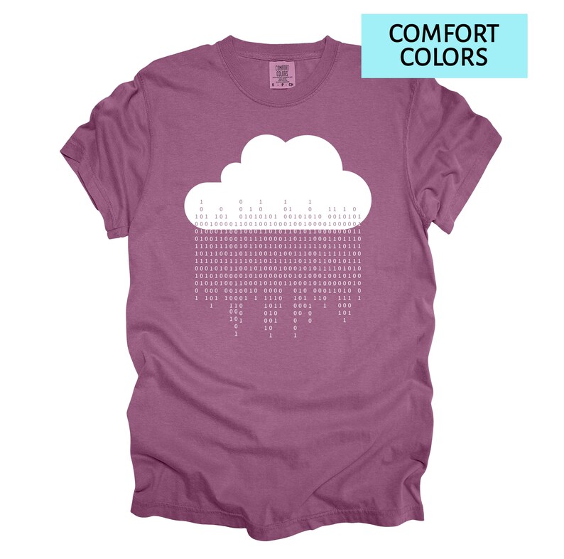 Pode incluir: Camiseta malva com um desenho de nuvem branca e c&oacute;digo bin&aacute;rio representando a chuva. O texto "COMFORT COLORS" est&aacute; em um ret&acirc;ngulo azul claro. A camisa tem um ajuste confort&aacute;vel.