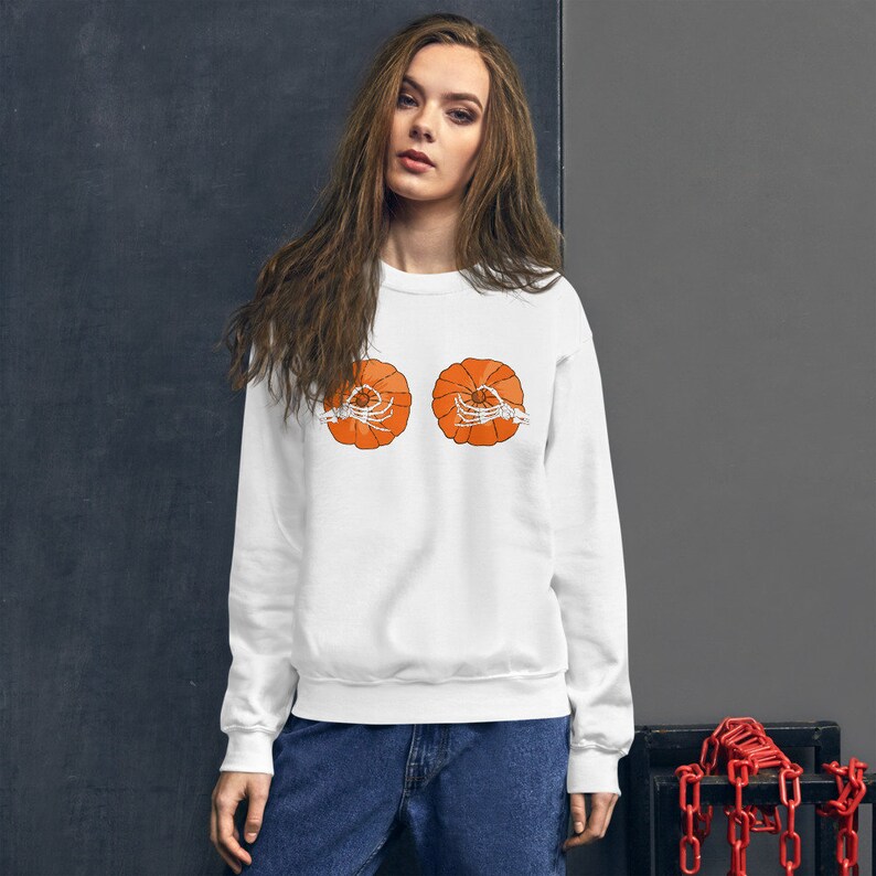 May include: White sweatshirt with a graphic of two orange pumpkins with skeleton hands inside.