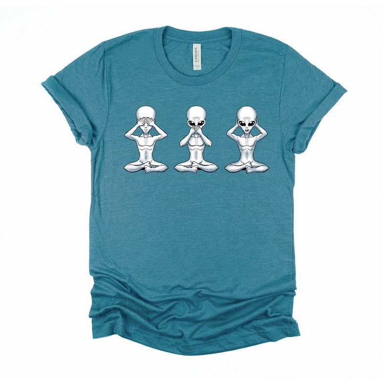 May include: A teal blue t-shirt featuring a graphic of three grey aliens in a yoga pose. The aliens are covering their eyes, mouth, and ears.