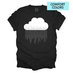Pode incluir: Camiseta preta com um desenho de nuvem branca composto por c&oacute;digo bin&aacute;rio. A camiseta tem o texto "COMFORT COLORS" em um ret&acirc;ngulo azul no canto superior direito. O desenho da nuvem est&aacute; centralizado na frente.