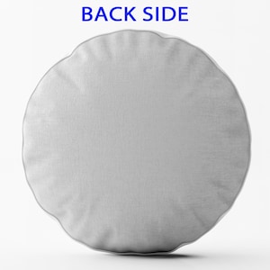 May include: A plain white round cushion with a smooth, textured fabric surface. The cushion is shown against a white background.