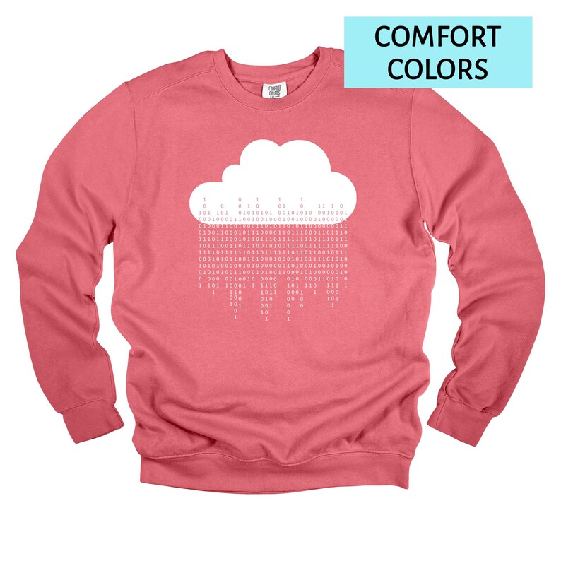 Op de afbeelding: Een koraalkleurige sweatshirt met een witte wolkengrafiek en binaire code regen. De tekst "COMFORT COLORS" staat in een lichtblauwe rechthoek. De sweatshirt heeft lange mouwen en een ronde hals.