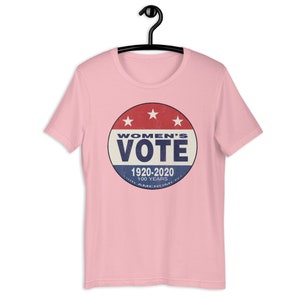 May include: Pink t-shirt with a vintage-style button featuring the text "Women's Vote" and the years "1920-2020" with the text "100 Years 19th Amendment" underneath.