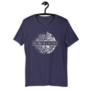May include: A navy blue t-shirt with a white graphic of a clock face with gears and the word "HOROLOGIST" printed below.