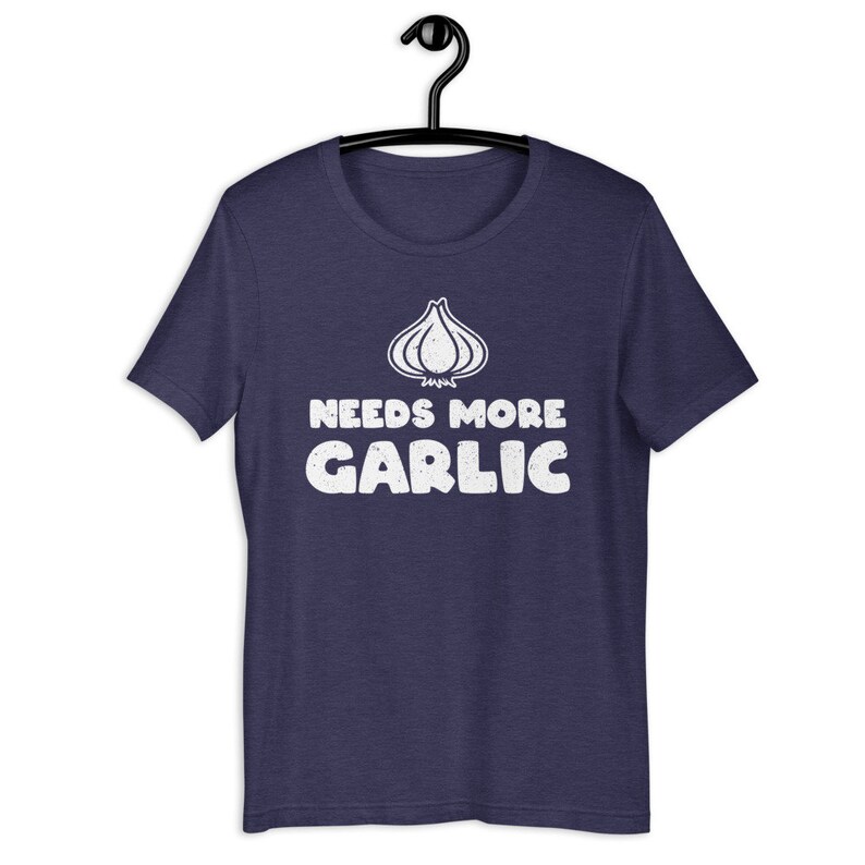May include: A navy blue t-shirt with a white graphic of a garlic clove and the text "Needs More Garlic".