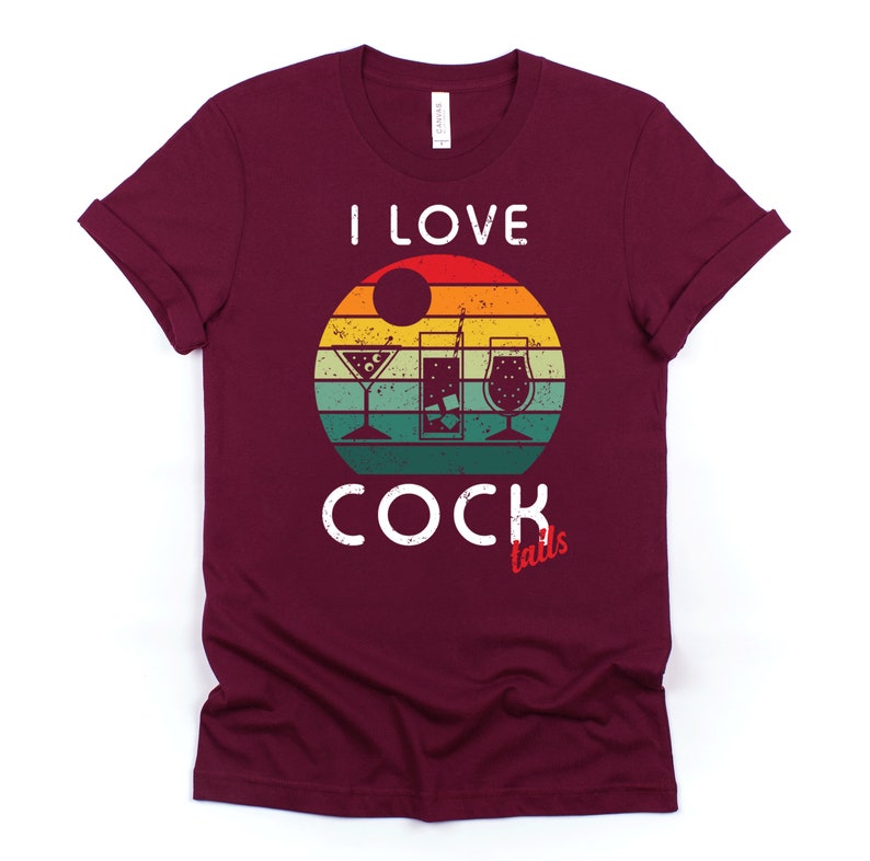 Op de afbeelding: Een maroon t-shirt met een vintage-stijl grafische afbeelding van een zonsondergang en drie cocktailglazen. De tekst "Ik hou van cocktails" is in wit op het shirt gedrukt.