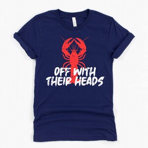 K&ouml;nnte beinhalten: Ein marineblaues T-Shirt mit einer roten Hummer-Illustration und dem Text "Off with their heads" in Wei&szlig;.