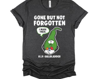 May include: A dark heather grey t-shirt with a cartoon green gallbladder holding colorful pills. The text on the shirt reads "Gone but not forgotten. I made these. R.I.P. Gallbladder."