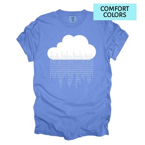 Pode incluir: Camiseta azul com um desenho de nuvem branca com chuva de c&oacute;digo bin&aacute;rio. O texto "COMFORT COLORS" est&aacute; em um ret&acirc;ngulo azul claro. A camiseta &eacute; de cor azul lisa.