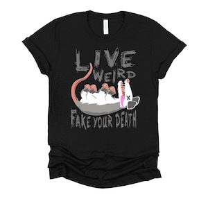 Op de afbeelding: Zwart T-shirt met een grijze afbeelding van een opossum met de tekst "Live Weird Fake Your Death" erop.